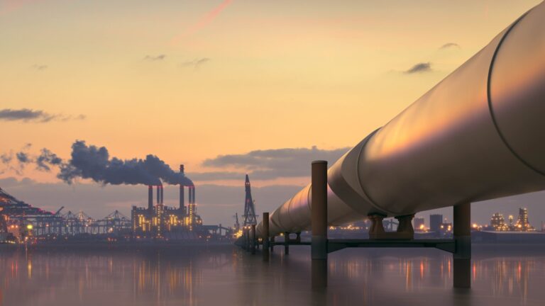 Oil pipeline in industrial district with factories at dusk